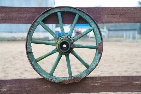 The carriage wheel hangs on the fence.