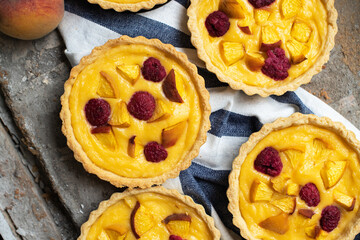 Summer custard tartlets with peaches and raspberry.