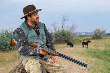 Hunter man in camouflage with a gun during the hunt in search of wild birds or game. Autumn hunting...