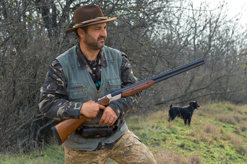 Hunter man in camouflage with a gun during the hunt in search of wild birds or game. Autumn hunting...