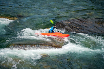 River kayaker in red kayak are paddling whitewatered river. Extreme sports and adrenaline concept. Removed logos.