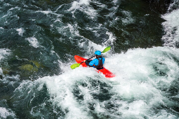 River kayaker in red kayak are paddling whitewatered river. Extreme sports and adrenaline concept. Removed logos.