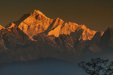 Beautiful first light from sunrise on Mount Kanchenjungha, Himalayan mountain range, Sikkim, India. Orange tint on the mountains at dawn.