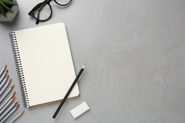 Flat lay composition with blank sketchbook on light grey stone table. Space for text