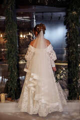The bride in a white wedding dress for the upcoming ceremony. View from the back.