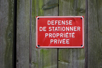 Closeup of private property panel in french (defense de stationner propriete privee) on wooden door traduction in english no parking private property