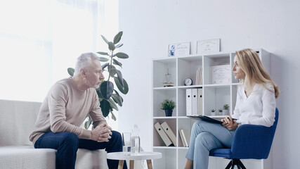 mature man having conversation with psychologist in consulting room