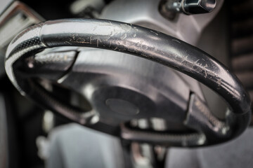Threadbare automotive black leather steering wheel of old auto close-up