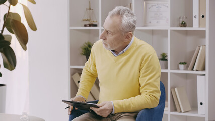 mature psychologist holding clipboard during consultation