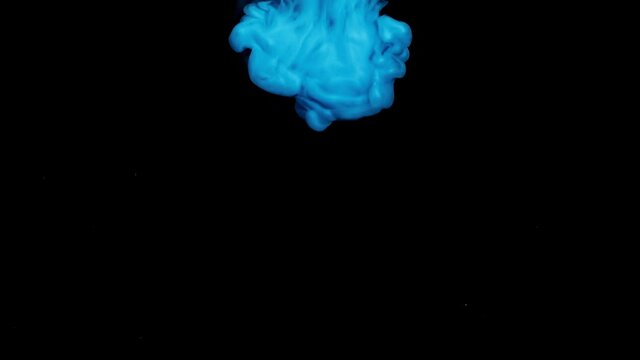 Bright blue-colored paint drop dissolving in water floats downward on background of black surface at studio illumination macro slow motion