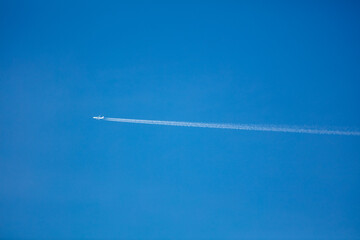Looking at a Plane in Flight leaving a Contrail in a Clear Blue Sky