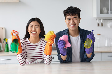 Positive asian lovers cleaning kitchen at new apartment