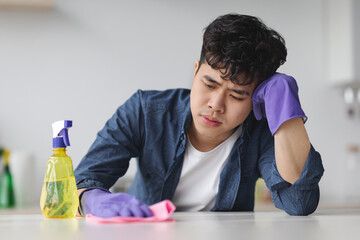 Exhausted young asian man with dust cloth, copy space