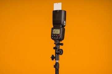 flash on a tripod for photography on a yellow background