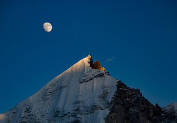 majestic himalayan mountain Mt. bhagirathi sisters in moonlight in the evening. peak is lit by last...