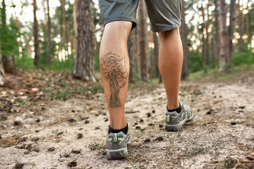 Muscular legs of caucasian man trekking along path