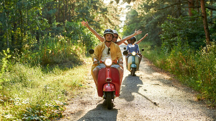 Happy young multiracial couples riding retro scooters