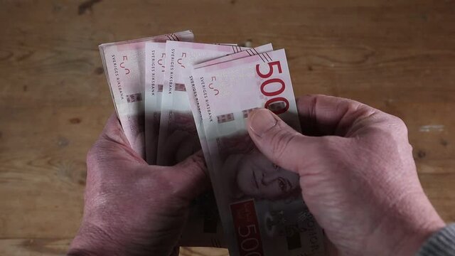 A hand fans out a stack of Swedish 500 kr notes.