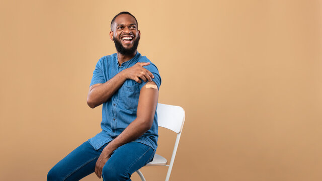 Coronavirus vaccination saves lives banner. Joyful black man posing with band aid on arm after receiving covid vaccine