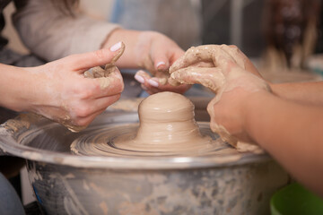 Cropped shot of two women working with clay on potters wheel