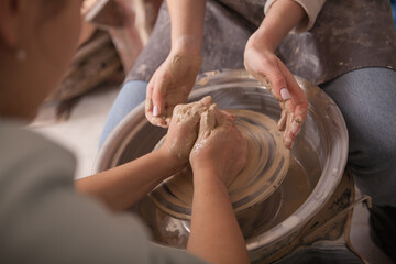 Cropped shot of professional potter teaching student how to work on potters wheel