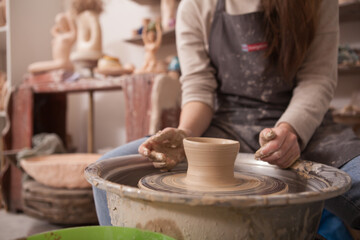 Unrecognizable woman working on potters wheel at art worksop, copy space