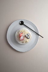 Anna Pavlova dessert with strawberry and blueberry on a white plate.