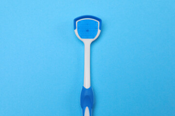 Tongue cleaner on blue background, top view