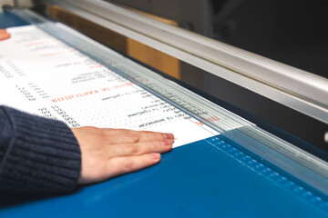 Worker with paper cutter machine in print house. Printing industry background