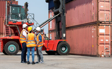 Fototapeta na wymiar Hispanic man harbor worker talking on the walkie-talkie radio and control loading containers at container warehouse. container yard port of import and export goods