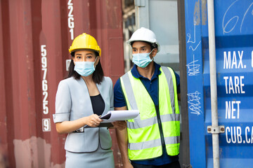 professional team man and woman worker wearing protection face mask during coronavirus and flu outbreak and wearing safety hardhat helmet at container yard or cargo warehouse