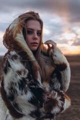 Beauty blondie young woman outdoors in fashion fur coat in sunset