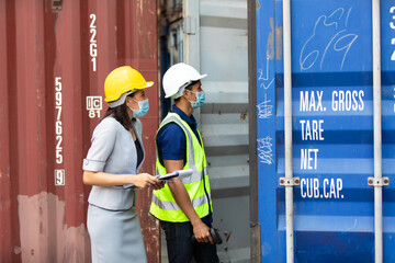 professional team man and woman worker wearing protection face mask during coronavirus and flu outbreak and wearing safety hardhat helmet at container yard or cargo warehouse