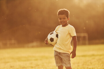 Illuminated by sunlight. African american kid have fun in the field at summer daytime