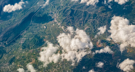 Earth surface landscape viewed from airplane under white clouds and blue sky from aerial view...