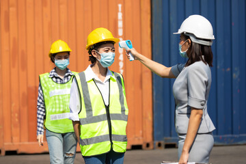 female manager measures temperature with a thermometer for employees before entering a container yard. import and export concept. Professional engineering team.