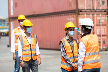 female manager measures temperature with a thermometer for employees before entering a container yard. import and export concept. Professional engineering team.