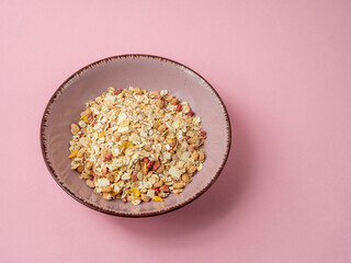 Muesli in a pink cup on a pink table. Muesli on a pink background.