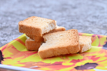 closeup the bunch brown rusk in the yellow plastic tray over out of focus yellow grey background.