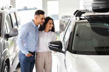 Middle-eastern family choosing new auto, standing by white vehicle