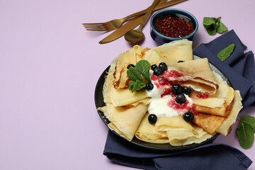 Concept of tasty food with crepes on violet background