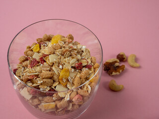 Muesli in a glass glass and berries on a pink table. Muesli on a pink background.