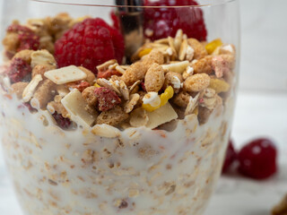 Muesli in a glass glass and berries on a white table. Muesli on a wooden white background.