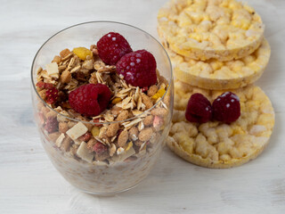 Muesli in a glass glass and berries on a white table. Muesli on a wooden white background.