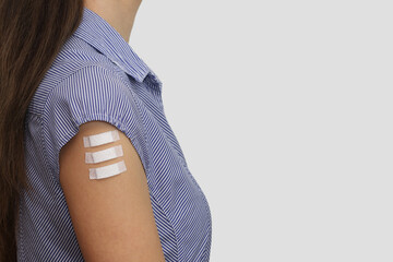 Three patches on the arm of a young woman. Symbol of three doses of covid-19 vaccinations,...