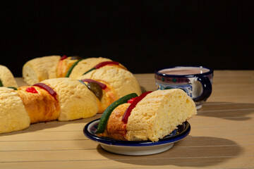 delicious rosca de reyes on wooden table, rosca de reyes ready to eat served in an artisanal plate with hot chocolate drink.