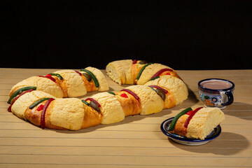 delicious rosca de reyes on wooden table, rosca de reyes ready to eat served in an artisanal plate...