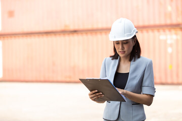 Asian business Women manager control loading Containers box from Cargo at container yard. Import and Export concept. Marine, carrier and logistic insurance