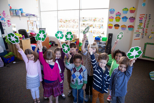 Portrait of children holding recycling symbols in school