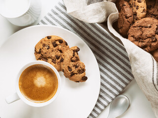 Cup of coffee with milk, chocolate cookie  and napkin on white background. Top view. Rustic food photography.